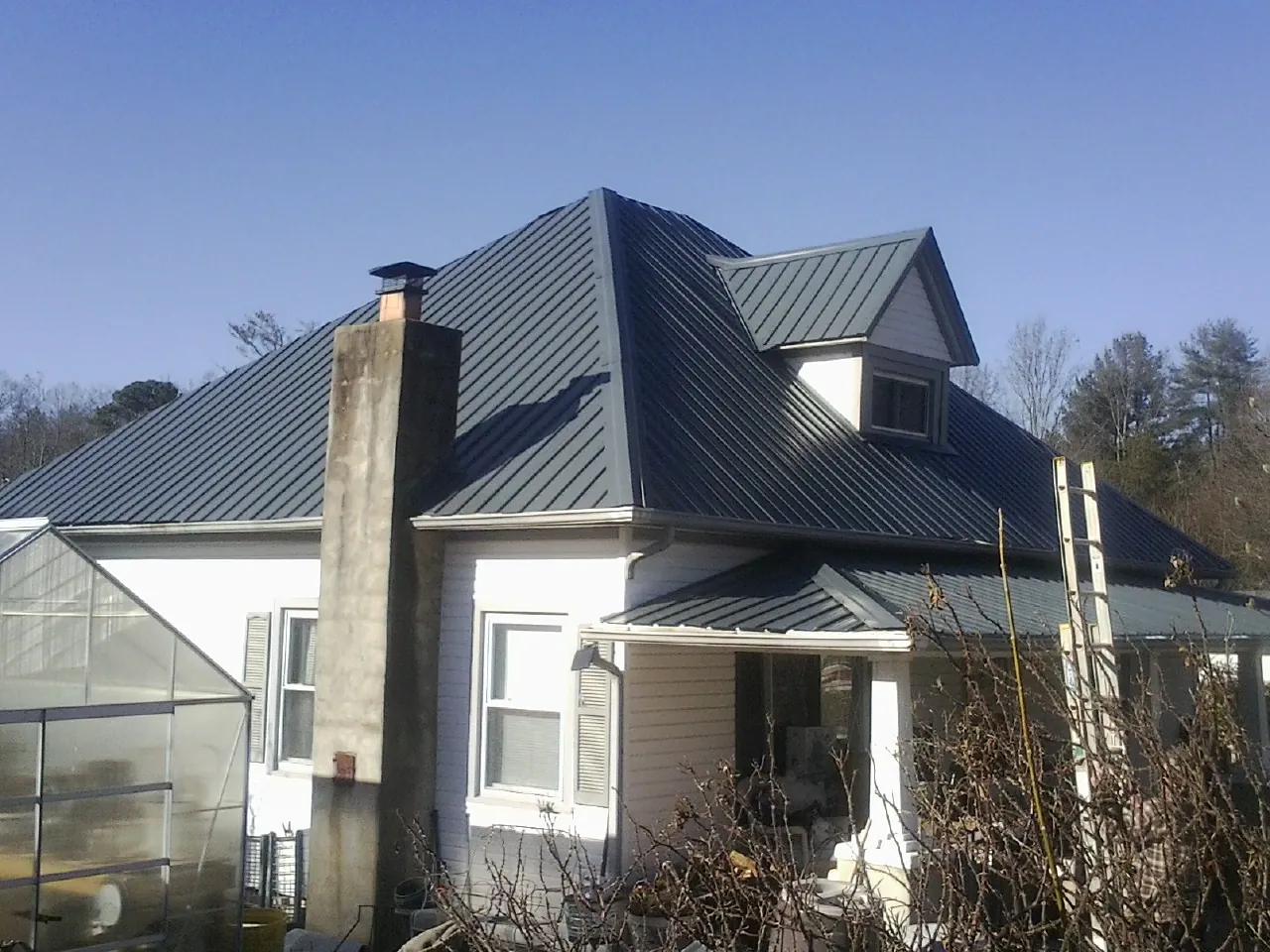 Dark blue standing seam metal roof on a white farmhouse with dormer — Slate & Tile Roof Repair by Roofing Brothers in Sarver