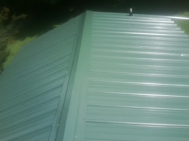 New green metal panels meeting at the ridge of a roof — Flat Roof Repair work by our crew in Sarver