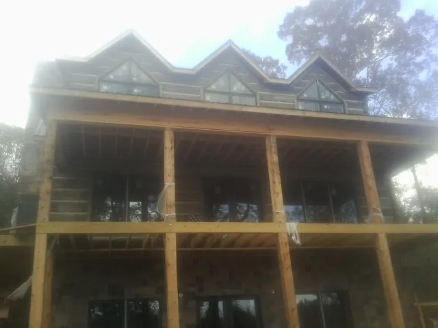 Dormers and porch framing on a large log home under construction — Roof Coating work by our crew in Sarver