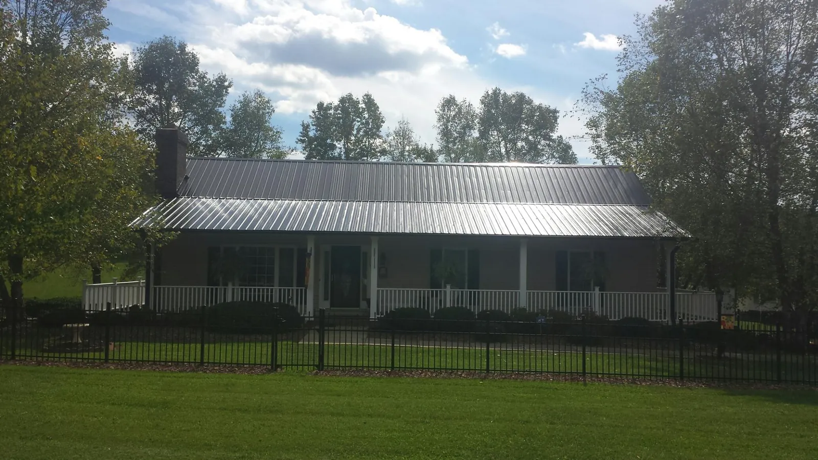 Gray metal roof on a brick ranch with a full width front porch — Gutter Guard Installation work by our crew in Sarver