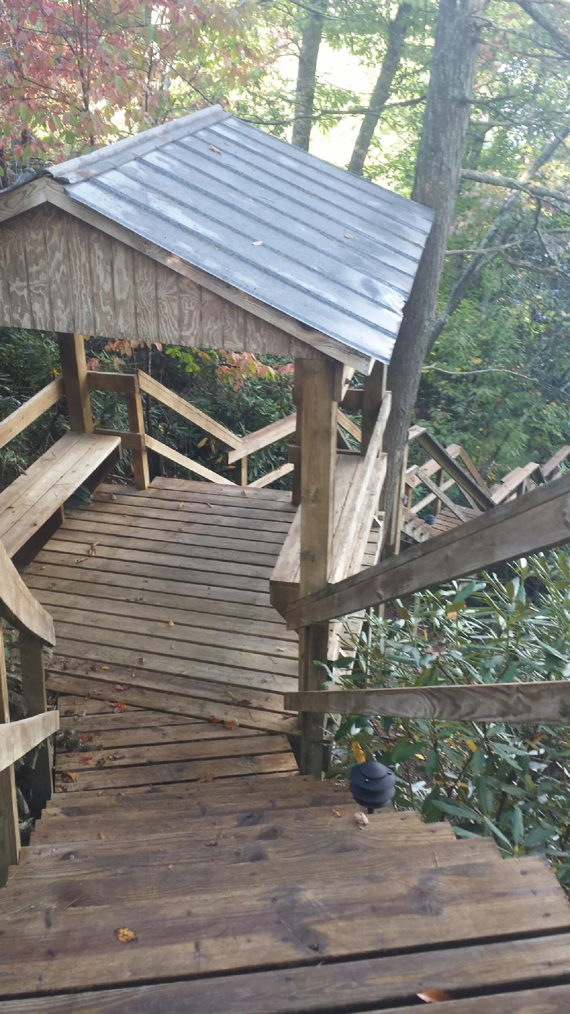 Metal roofed shelter over wooden steps on a wooded walkway — Skylight Repair & Installation work by our crew in Sarver
