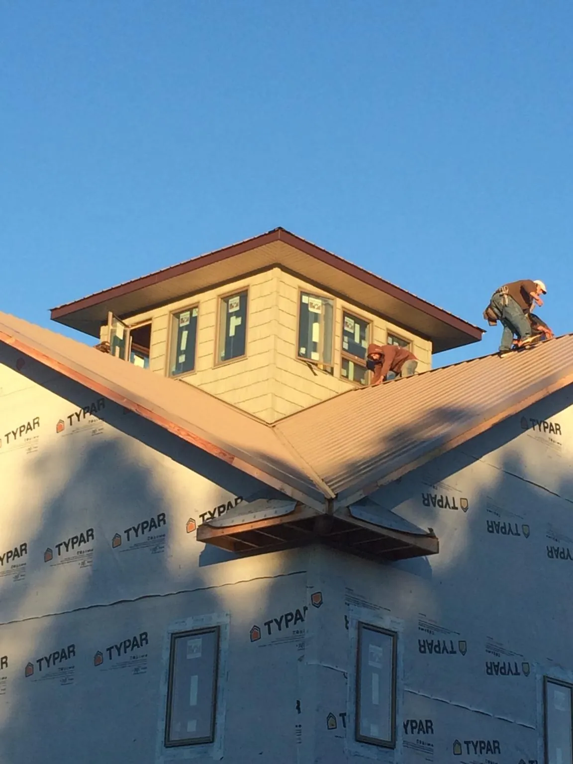 Roofers working around a rooftop cupola on a new metal roof at sunset — Roof Waterproofing in Sarver by Roofing Brothers